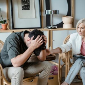 A supportive therapist provides comfort during a counseling session in a cozy office.
